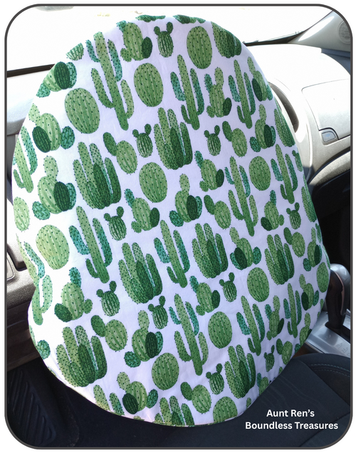 Steering Wheel cover with green cactus pattern on white fabric slipped over top of car steering wheel