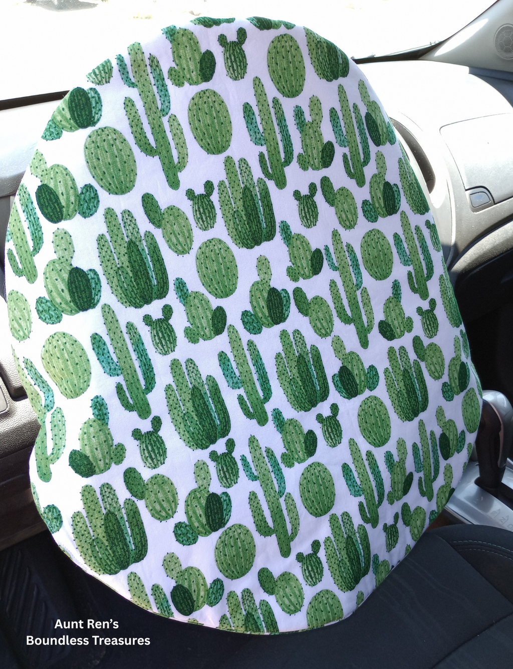 Steering Wheel cover with green cactus pattern on white fabric slipped over top of car steering wheel