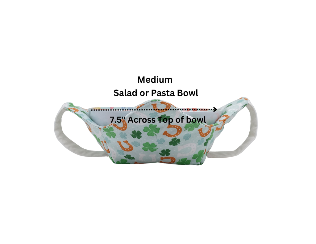 Fabric bowl cozy with shamrocks and horse shoes on white fabric with a white strap holding a white bowl with measurements.