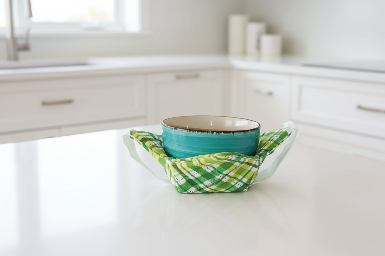 Turquoise bowl with a green and white checkered bowl cozy with a white strap in a kitchen setting
