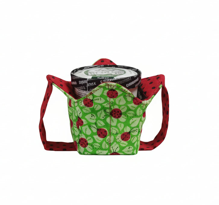 Ladybugs on green fabric with leaves on outside and red fabric with black polka dots on inside with a matching strap holding pint of ice cream