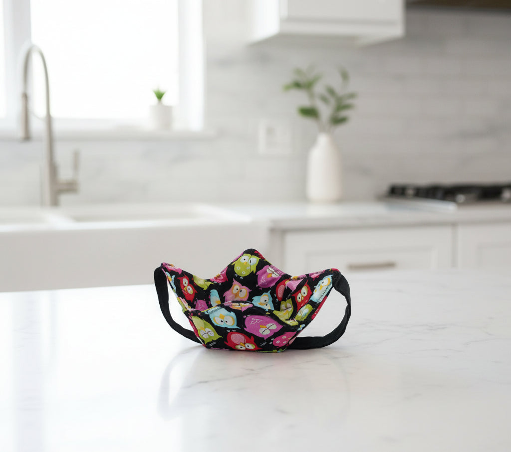Bowl Cozy with black strap for hand support features colorful owls on black fabric.
