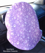 paws on purple fabric slipped over top of car steering wheel