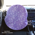 paws on purple fabric covering steering wheel
