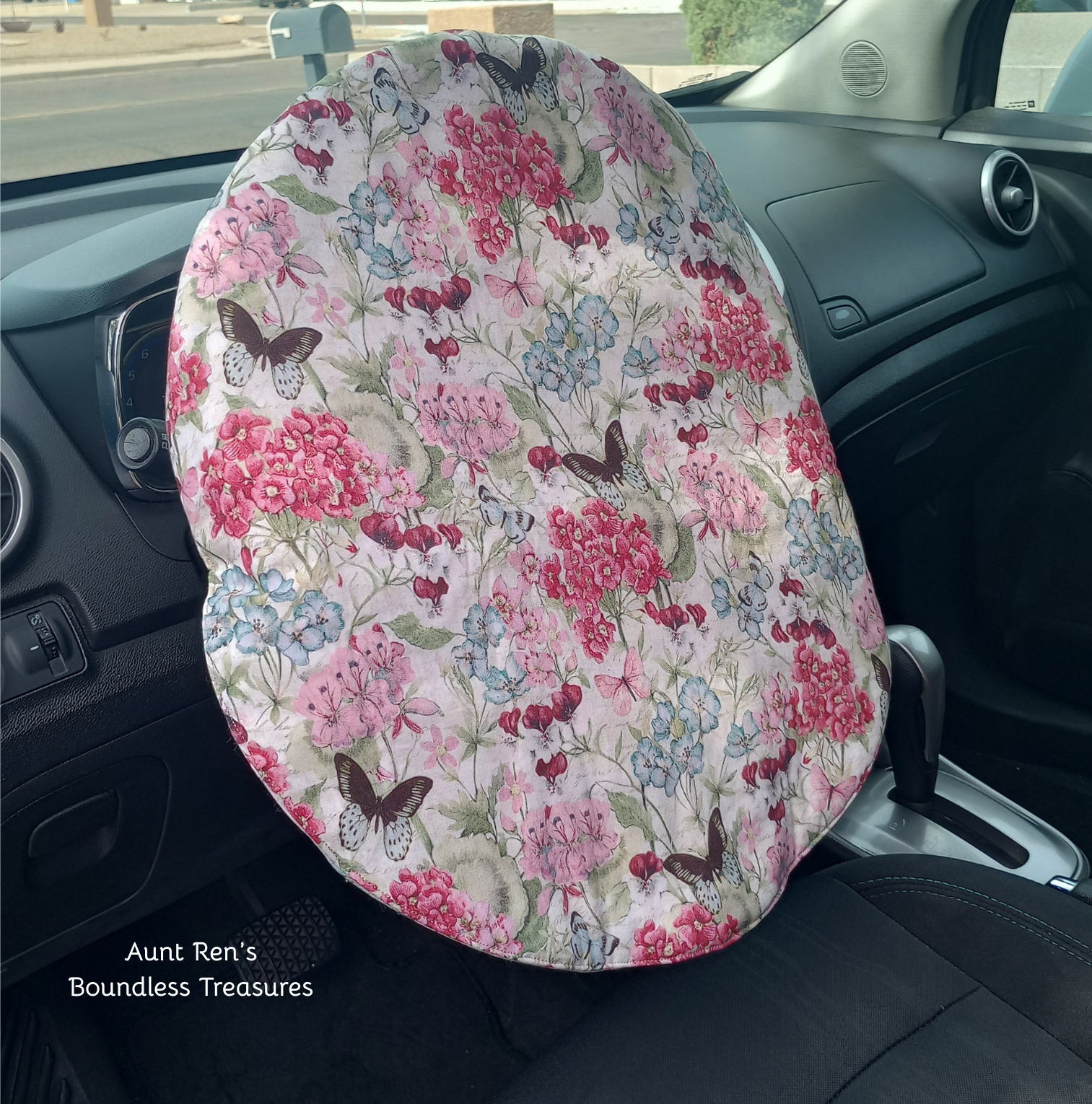 Flowers and butterflies on cream fabric covering a steering wheel