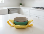 Bright yellow fabric bowl holder with a strap for hand support
