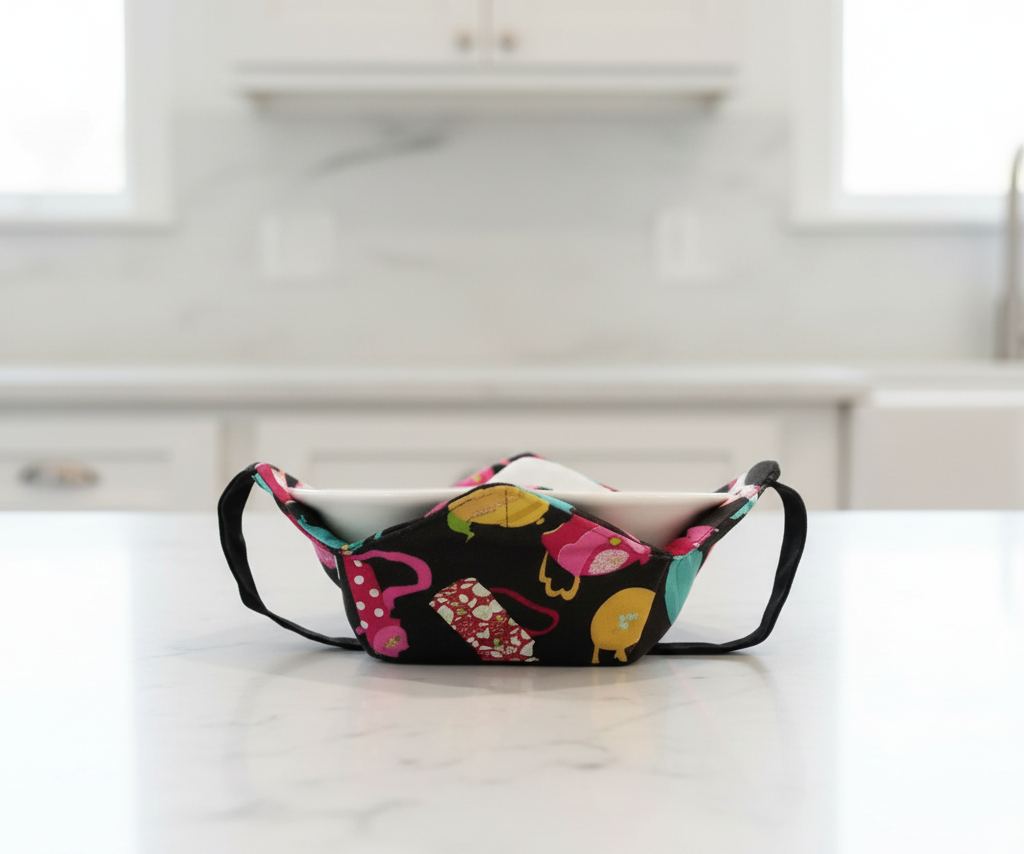 multicolor teapots on black fabric, bowl hot pad with black handles in a kitchen