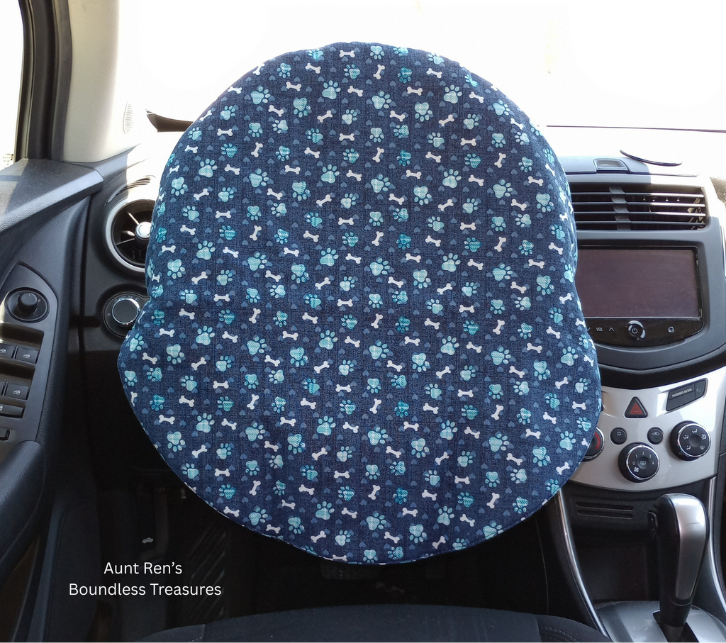 blue paw prints and white dog bones on a dark blue fabric covering a steering wheel