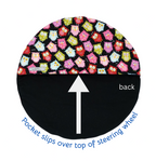 Steering wheel cover with owl pattern on top and black base with arrow and text on bottom, on a white background.