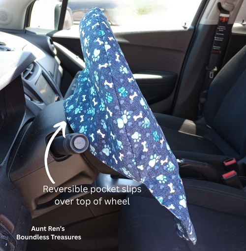 side view of blue steering wheel cover with paw prints and dog bones